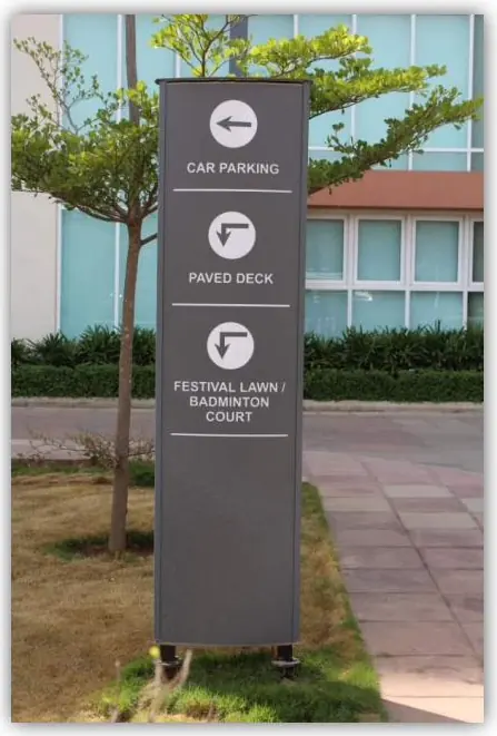 Freestanding directional pylon sign at a residential development listing car parking, paved deck and badminton court