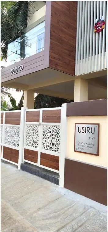 House name plate mounted on a compound wall beside a decorative jalli screen