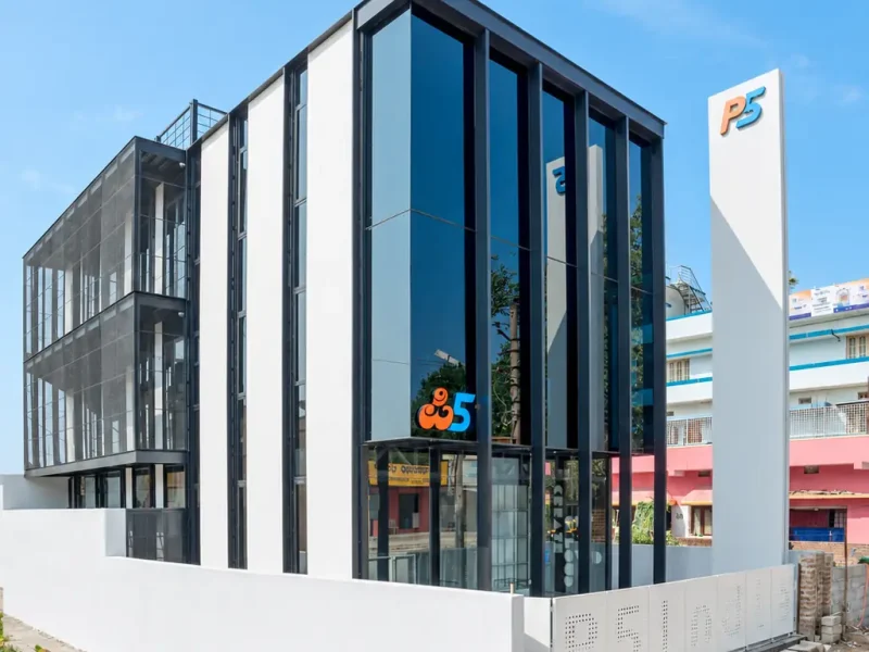 The P5 India building under a blue sky: dark glass and white fins on a corner plot, the P5 logo on the glass, and the white P5 pylon beside it