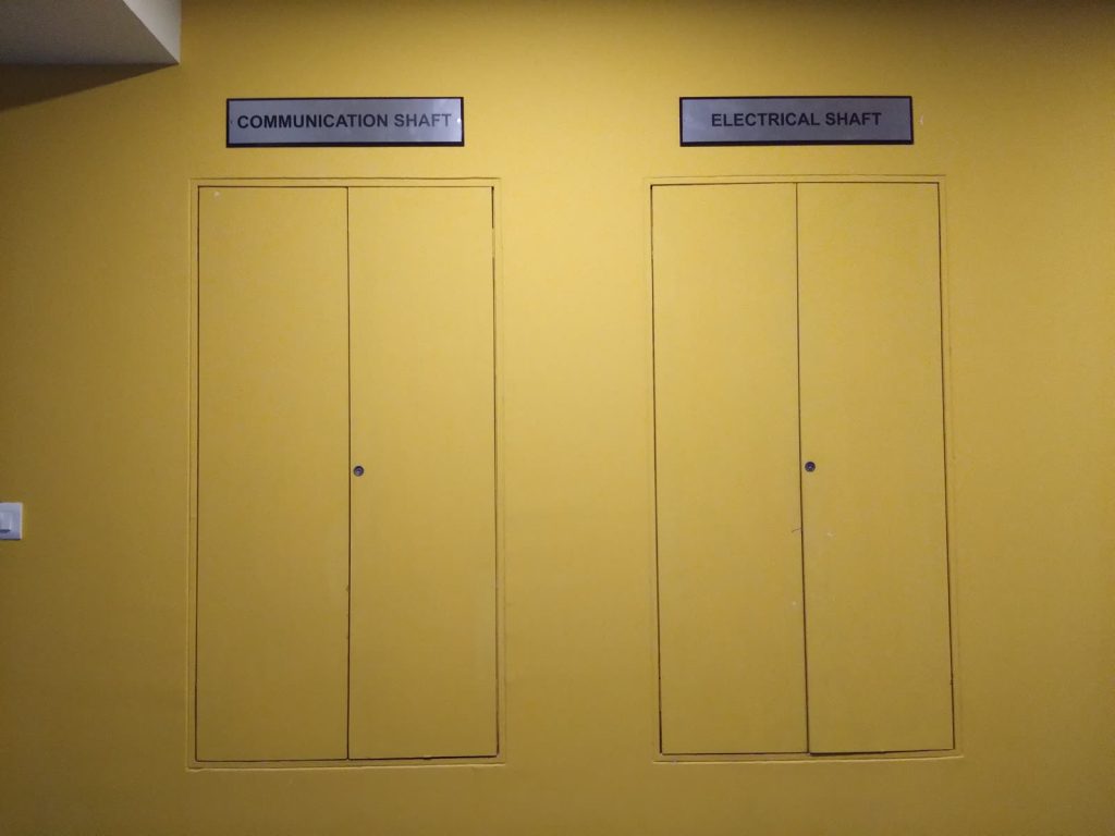 Two small plates above service doors reading Communication Shaft and Electrical Shaft