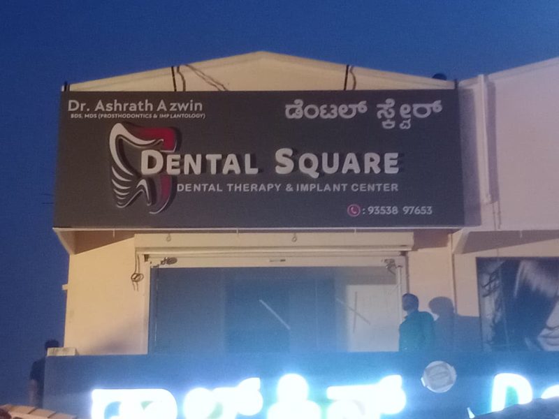 Dental Square fascia board with white letters and a tooth logo, at dusk