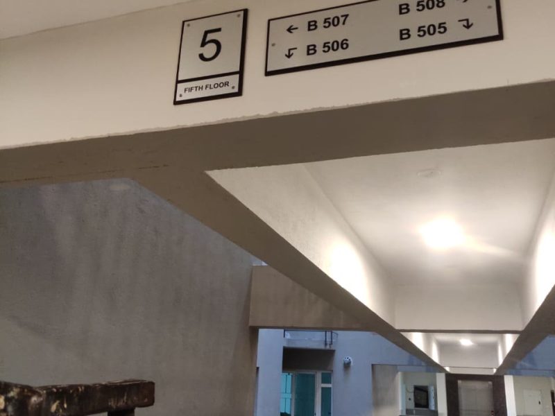 Floor number plate and flat direction board fixed to a beam in an apartment corridor