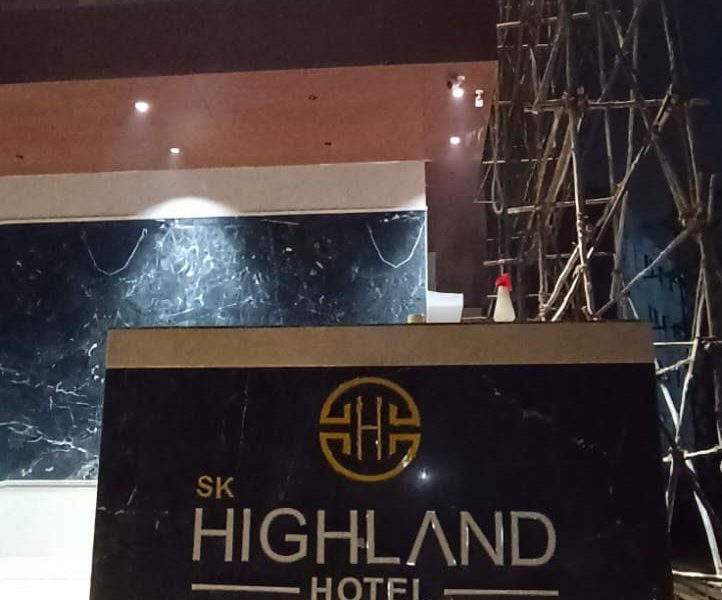 Low monument sign reading SK Highland Hotel, lit at night