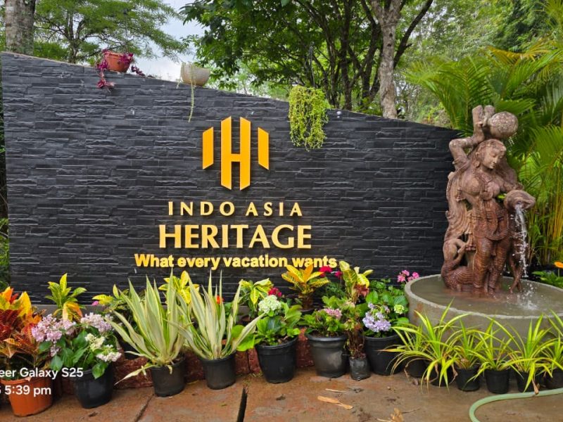 Indo Asia Heritage logo and name on a dark stone garden wall with planting in front