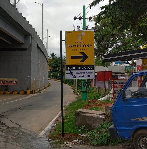Yellow roadside pole board with an arrow pointing to Brigade Symphony