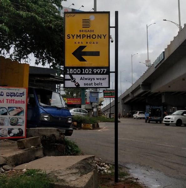 Yellow pole board with a left arrow for Brigade Symphony beside a flyover