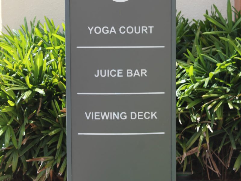 Grey direction totem with an arrow to Yoga Court, Juice Bar and Viewing Deck, in daylight