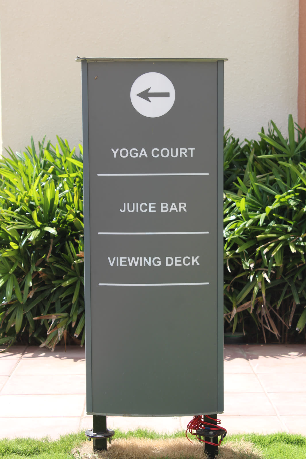 Grey direction totem with an arrow to Yoga Court, Juice Bar and Viewing Deck, in daylight