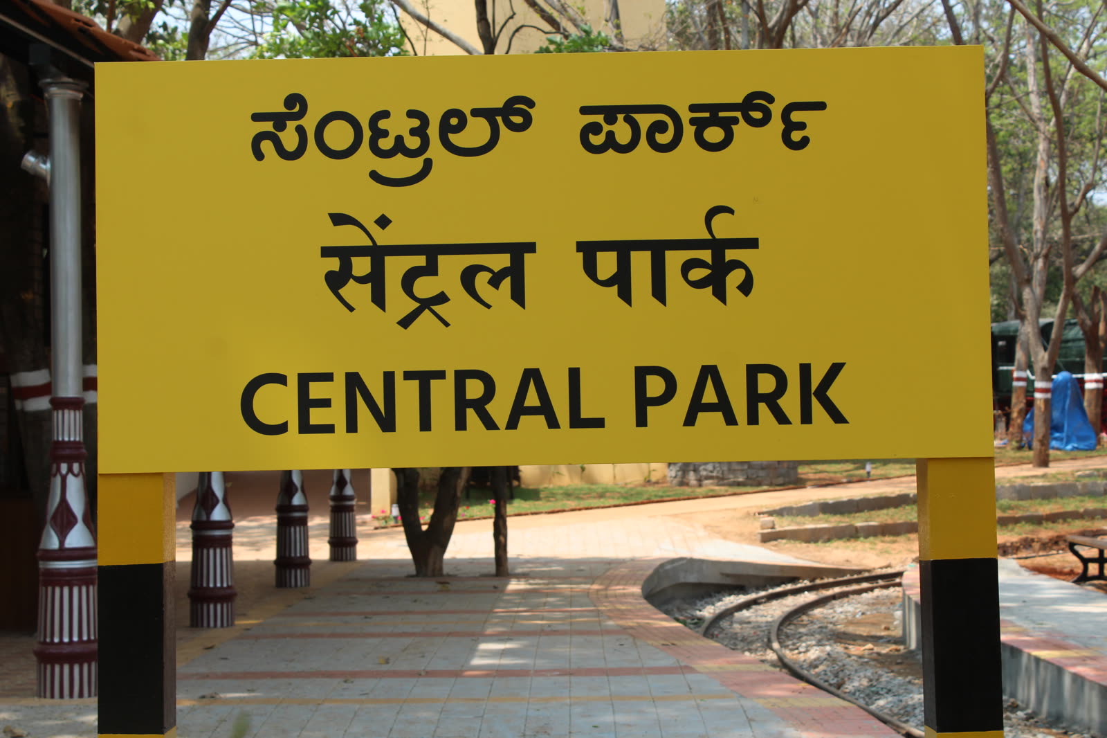 Yellow station-style name board reading Central Park in Kannada, Hindi and English