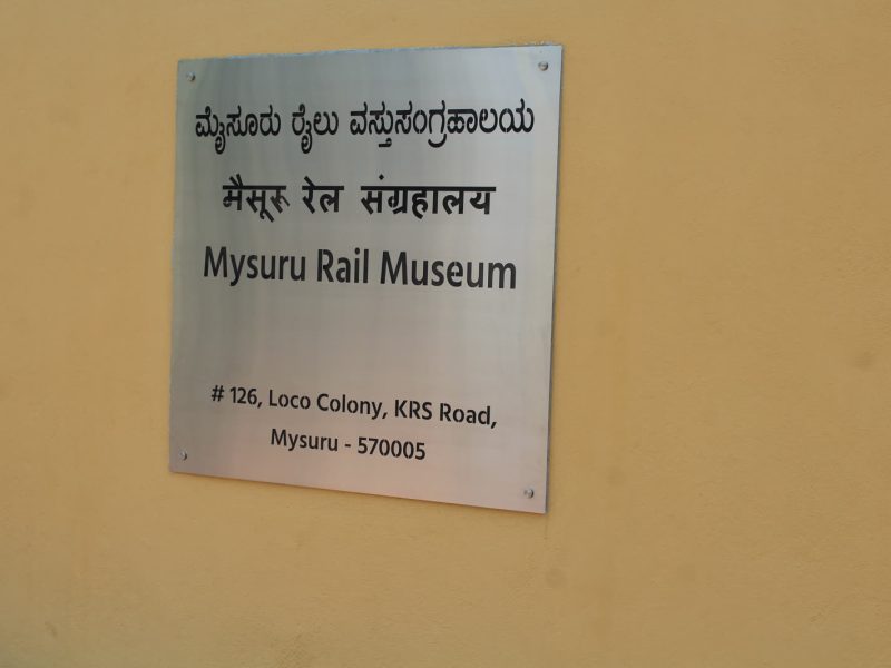 Brushed steel address plate reading Mysuru Rail Museum in three languages, 126 Loco Colony, KRS Road