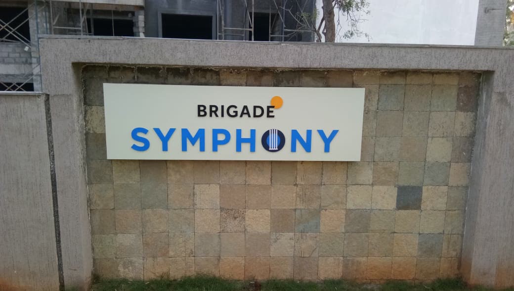 Brigade Symphony name board on a stone-clad compound wall
