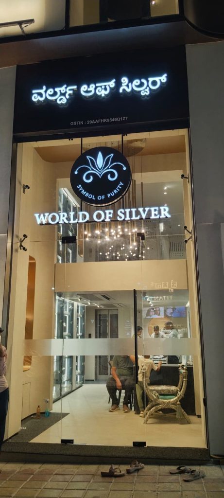 World of Silver showroom front with lit letters and a round logo, at night