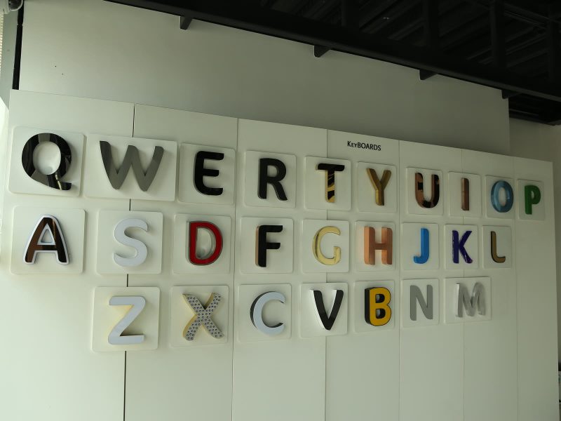 A wall of raised letters laid out like a keyboard, Q to M, each letter in a different letter type and finish